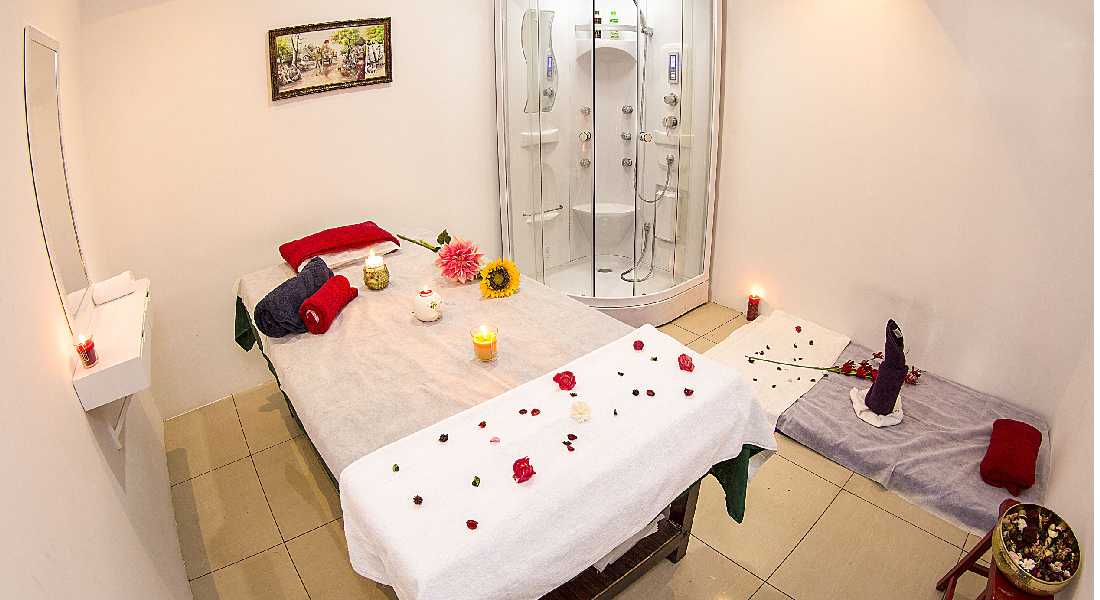 Spa and massage centre arranged with white towels, candles and flowers.
